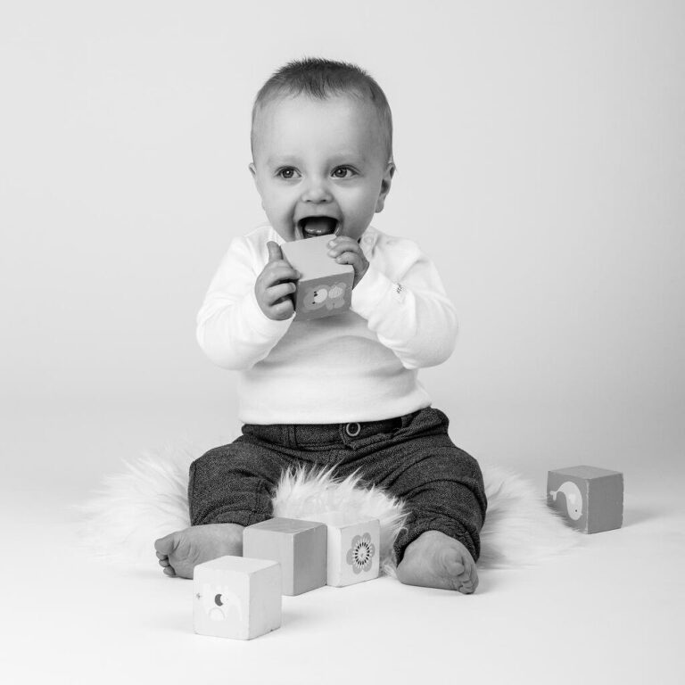 Bild av skrattande liten tandlös pojke som leker med klossar i studio